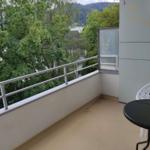 Balkon mit Tisch und Stuhl, Blick auf Bäume und Berge