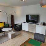Wohnzimmer mit Sofa, Fernseher und Esstisch
