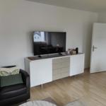 Ein Wohnzimmer mit Fernseher, Schrank und Sessel.