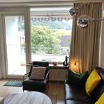 Wohnzimmer mit Blick auf grüne Landschaft. Sofa und Sessel mit Kissen.