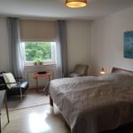 Schlafzimmer mit Bett, Sessel, Fenster und Wandbild.