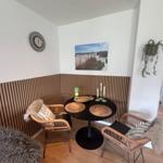 Runder Tisch mit zwei Stühlen, Wandbild und Wanduhr im Ecke.