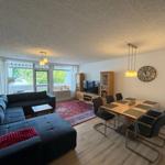 Wohn- und Essbereich mit Sofa, Tisch und Stühlen sowie TV und Wanduhr.