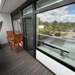 Terrasse mit Holzstühlen und Blick ins Schlafzimmer mit Bett und Fenster.