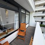 Terrasse mit Holzstuhl und Blick in Wohnraum mit Bett und Fenster