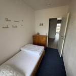 Schlafzimmer mit Bett, Holzkommode und Wanddekoration.