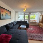 Großer Wohnbereich mit Sofa, Teppich und TV. Blick auf Balkon.