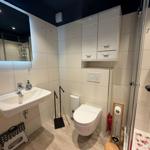 Badezimmer mit Dusche, WC und Waschbecken mit beleuchtetem Spiegel.