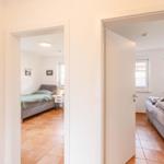 Two bedrooms with beds, windows, and terracotta flooring are visible.