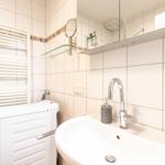 Bathroom with washing machine, mirror, and towel warmer on the wall.