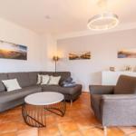 Living room with gray sofa, armchair, and round table on terracotta floor.