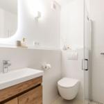 Badezimmer mit Dusche, Toilette und Waschbecken mit Holzunterschrank.