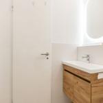 Badezimmer mit Waschbecken, Spiegel und Handtuchhalter.