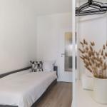 Ein Schlafzimmer mit Bett, Kleiderschrank und Vasen mit Trockenblumen.