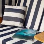 Strandliege mit Streifenkissen und Surf-Magazin.