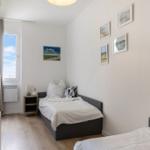 Schlafzimmer mit zwei Betten, Fenster und Wandbildern.