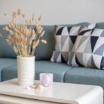 Ein grauer Sofa mit Kissen und Tisch mit Vasen und Muscheln.