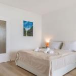 Schlafzimmer mit Bett, Nachttischen und Wandbild. Tür und Holzboden sind sichtbar.