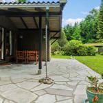 Terrasse mit Steinplatten, Holzstühlen und Blick auf grünen Garten.