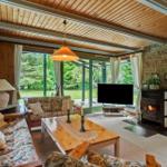 Wohnzimmer mit Kamin, TV und großem Fensterblick auf Garten