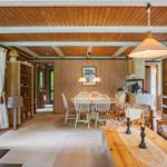 Wohn- und Essbereich mit Holzdecke, Esstisch, Sofa und Kamin.