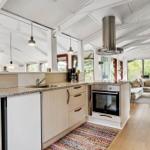 Küche mit Arbeitsplatte, Spüle und Backofen. Wohnbereich mit Sofa und Fenstern.