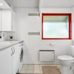 Badezimmer mit Toilette, Waschmaschine und rotem Fensterrahmen.