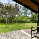 Holzterrasse mit Bank und Blick auf grünen Rasen und Bäume.