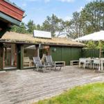 Haus mit Holzterrasse, Gartenmöbel und Sonnenschirm. Grün getönter Holzaufbau mit Glasfront.