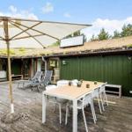Terrasse mit Tisch, Stühlen und Sonnenschirm. Grün verkleidetes Gebäude mit Dachbodenfenster.