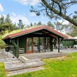 Moderne Holzhütte mit Grasdach, Terrasse und Garten. Außenbereich mit Sitzgelegenheiten.