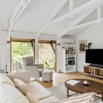 Wohnzimmer mit Kamin, Sofa, Fernseher und Blick auf Garten