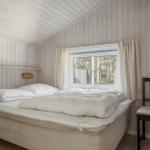 Schlafzimmer mit Bett, Fenster und Stuhl. Holzwände und Decke.
