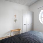 Schlafzimmer mit runden Fenster, Bett und Kleiderschrank.