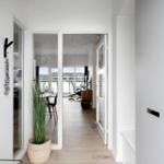 Haus mit modernem Eingangsbereich, Glaswand und Pflanze. Blick in Wohnbereich mit Balkon.