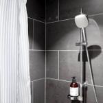 Dusche mit Handbrause und Duschvorhang aus Streifenstoff.