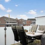 Terrasse mit Tisch und Stühlen, Blick auf Gebäude mit Schild Feriecenter Sondervig.
