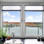 Küche mit Blick auf Wasser und Landschaft durch große Fenster.