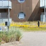 Privatparkplatz vor modernem Gebäude mit runden Fenstern und Grasflächen.