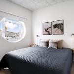 Schlafzimmer mit runden Fenster, Bett und zwei Wandbilder.