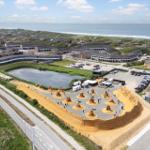 Strandkunstwerk mit Sandskulpturen am Meer. Parkplatz und Gebäude im Hintergrund.