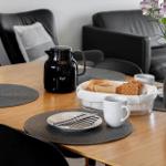 Esstisch mit Teller, Kaffeekanne und Blumenarrangement