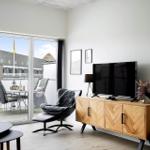 Wohnzimmer mit TV, Holzschrank und Balkonansicht. Sicht auf Terrasse und Gebäude.