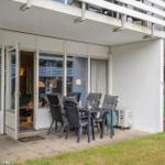 Terrasse mit Sitzgruppe und Blick ins Haus. Gartenbereich mit Pflanzen und Flagge.