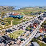 Luftbild von Ferienort mit Strand, Parkplätzen und Gebäuden.