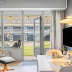Wohnbereich mit Essbereich, TV und Blick auf Außenbereich.