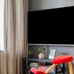 TV an der Wand, roter Stuhl und Bücherregal