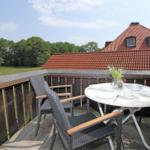 Terrasse mit Tisch und Stühlen, Blick auf Dach und Wald.