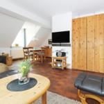 Wohn- und Essbereich mit Holzmöbeln, TV und Schlafzimmerwand.