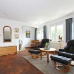 Wohnzimmer mit zwei schwarzen Sesseln, Holztisch und Terrassentür.